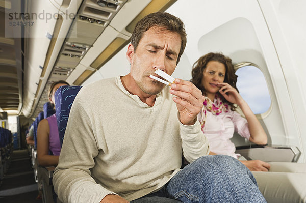 Mann riecht Zigaretten und Frauen ärgern sich im Economy Class Flugzeug