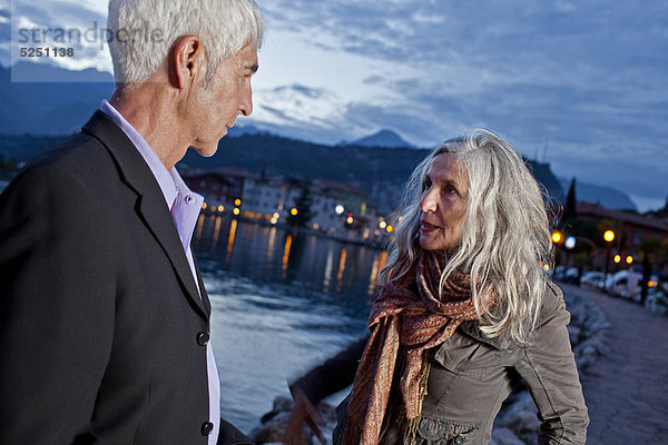 Seniorenpaar am Wasser schaut sich in die Augen  Italien