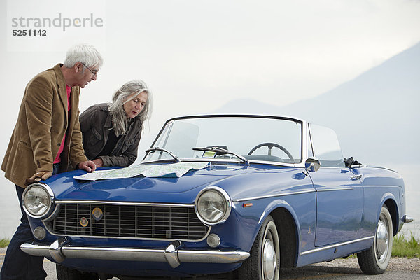 Seniorenpaar mit Straßenkarte an einem Cabrio  Italien  Gardasee