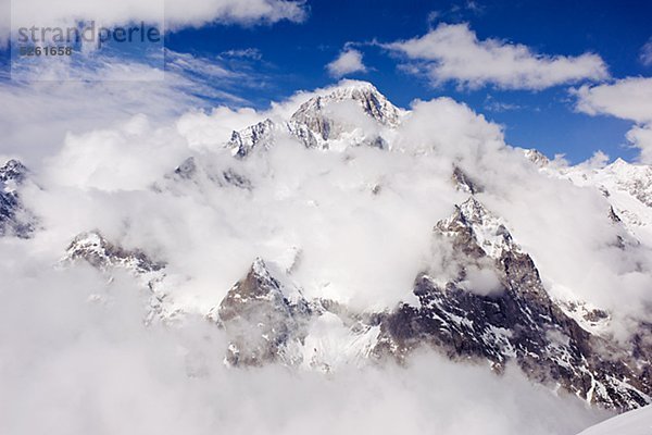 Snowcapped Spitzen hinter Wolken