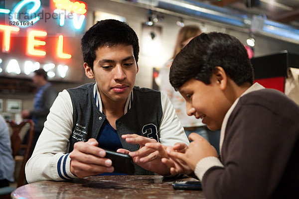 Zwei Brüder mit Smartphone im Cafe