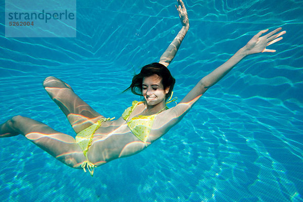 Junge Frau schwimmt unter Wasser im Schwimmbad