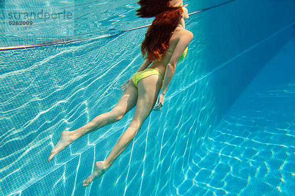 Junge Frau schwimmt unter Wasser im Schwimmbad