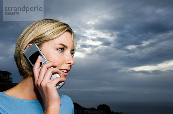 Frau nutzt Handy gegen Sturmwolken