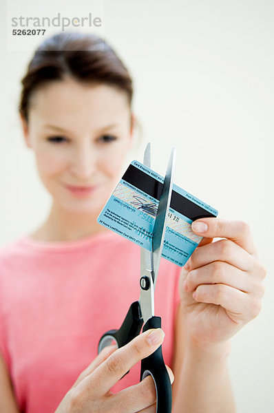 Frau schneidet Kreditkarte mit Schere