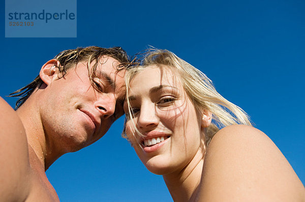 Young Couple looking at Kamera gegen blauen Himmel