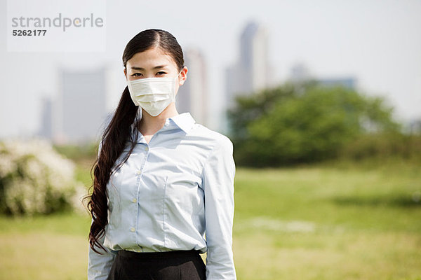 Junge Geschäftsfrau mit Verschmutzungsmaske