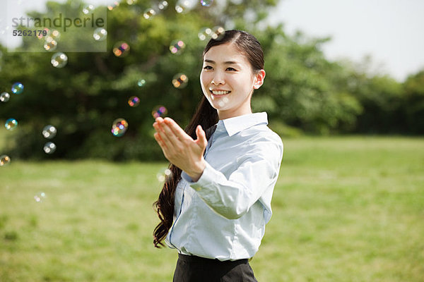 Porträt einer jungen Geschäftsfrau  die Blasen berührt