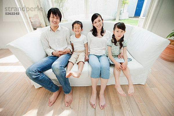 Familie mit zwei Kindern auf Sofa  Porträt