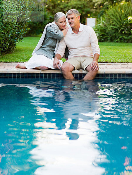 Paar am Pool im Garten sitzend