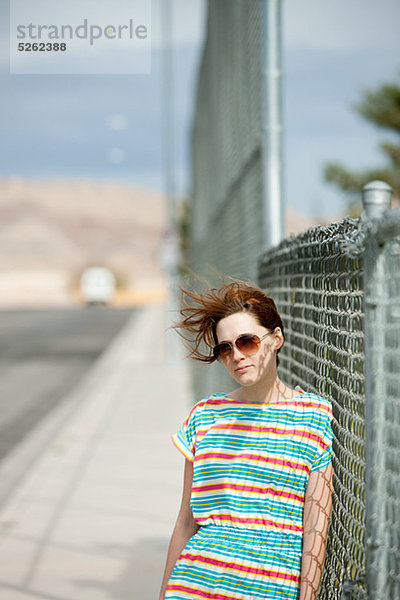 Young Woman leaning auf Drahtzaun