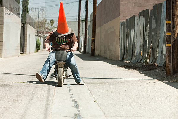 Mann mit Verkehrskegel am Kopf  Motorradfahren