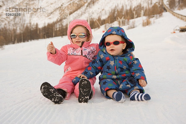 Porträt von Bruder und Schwester im Schnee sitzend