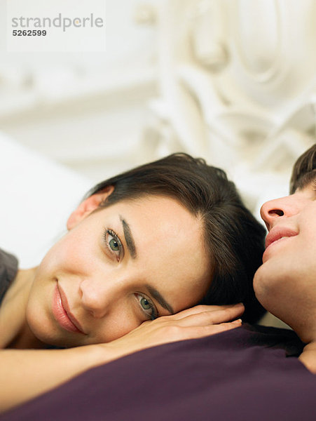 Young Couple lying in Bed  Frauenkopf auf Schulter des Mannes