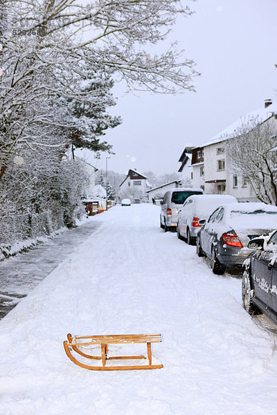 Schlitten und geparkte Autos im Winter