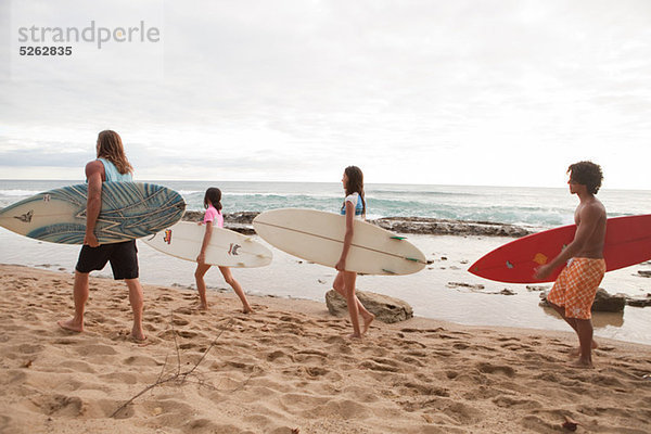 Vier junge Freunde mit Surfbrettern am Strand