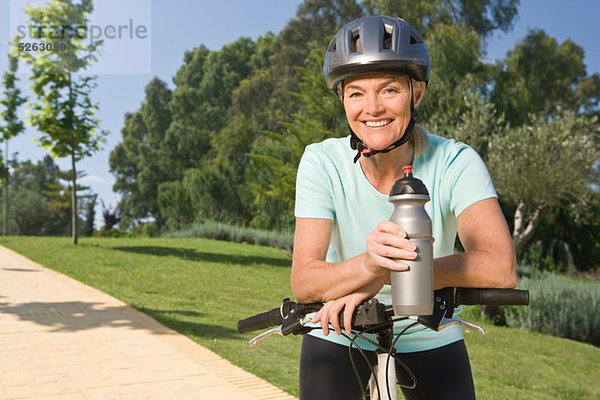 Reife Frau Radfahrer tragen  Helm und Betriebs-Flasche