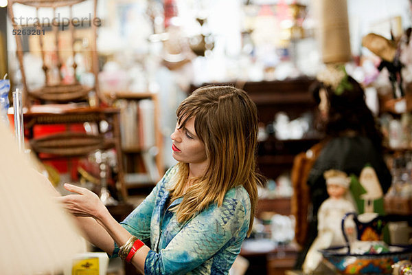 Frau inspiziert Artikel für den Verkauf im Antiquitätenladen