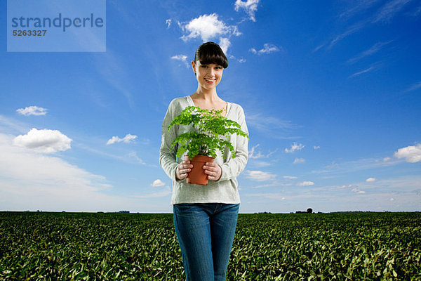 Young Woman holding Plant im Feld