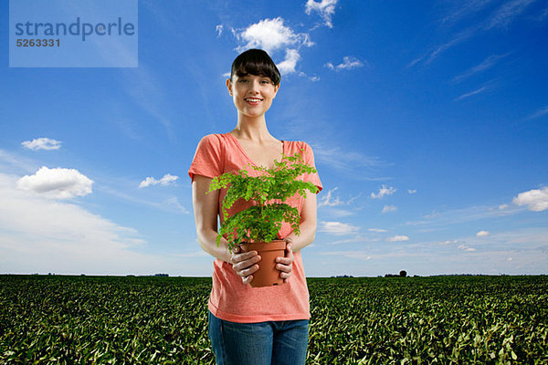 Young Woman holding Plant im Feld