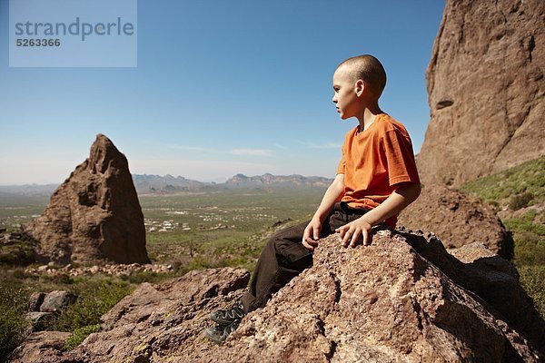 Junge sitzend auf einem Felsen in der Wüstenlandschaft