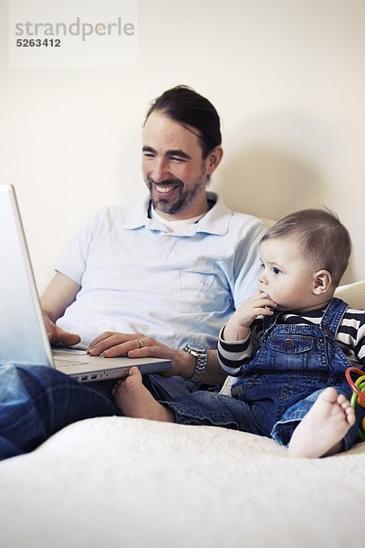 Man using Laptop mit Baby neben ihm