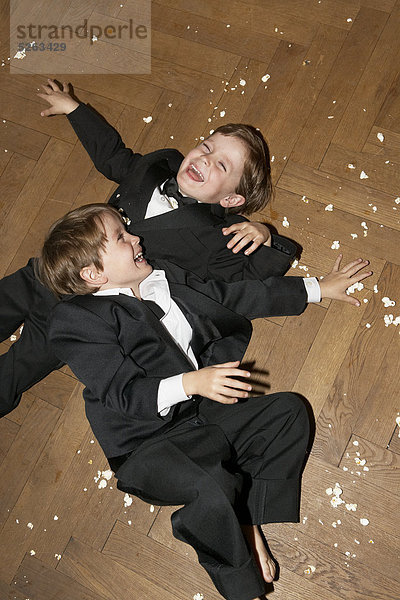Zwei jungen lying on Floor spielen mit popcorn