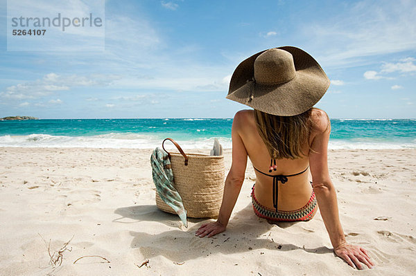Frau sitzend am Sandstrand  Mustique  Grenadinen