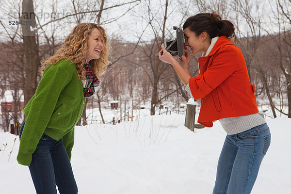 Teenager-Mädchen nehmen Foto von Freund im Schnee