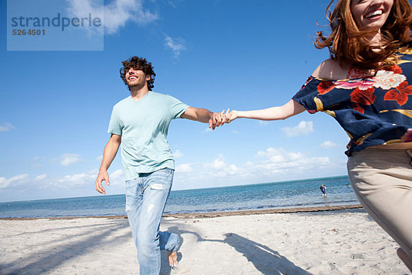 Junge Paar hält Hände am Strand