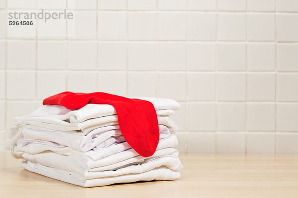 Haufenweise saubere weiße Wäsche und rote Socken