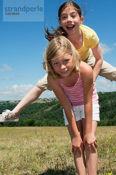 Zwei Mädchen spielen Leapfrog im Feld