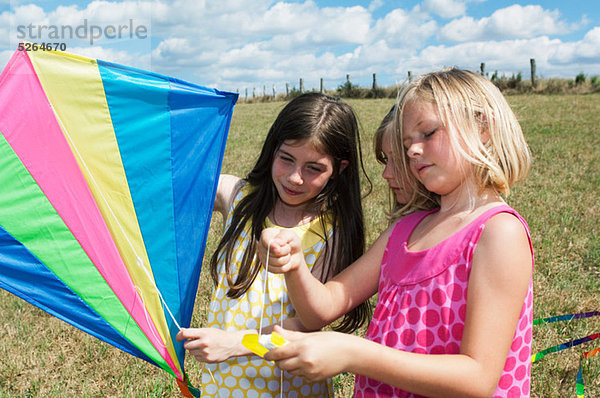 Drei Mädchen halten Kite in Feld