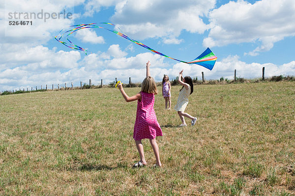 Drei Mädchen-flying Kite in Feld