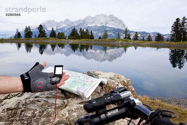 Mountainbiker hält ein GPS-Gerät an einem See