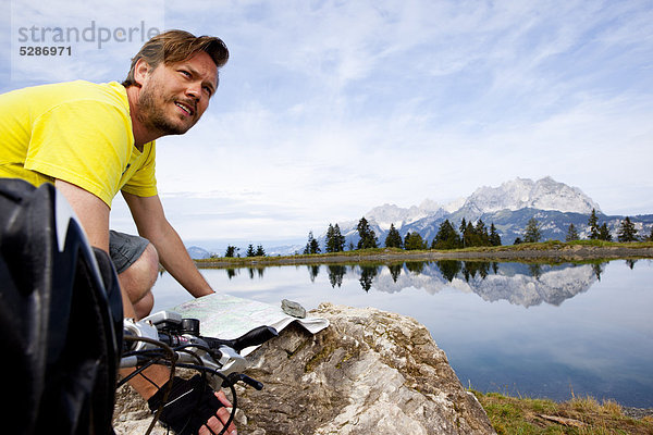 Mann mit Mountainbike an einem Felsen orientiert sich