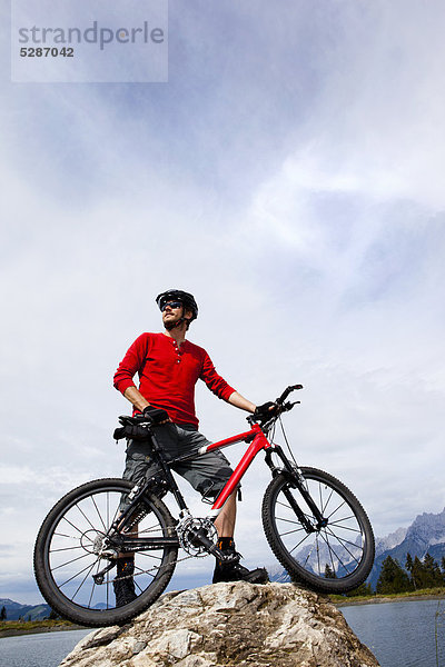 Mann mit Mountainbike auf einer Felsspitze