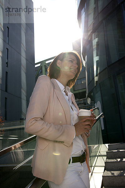 Lächelnde Geschäftsfrau mit Coffee to Go im Freien