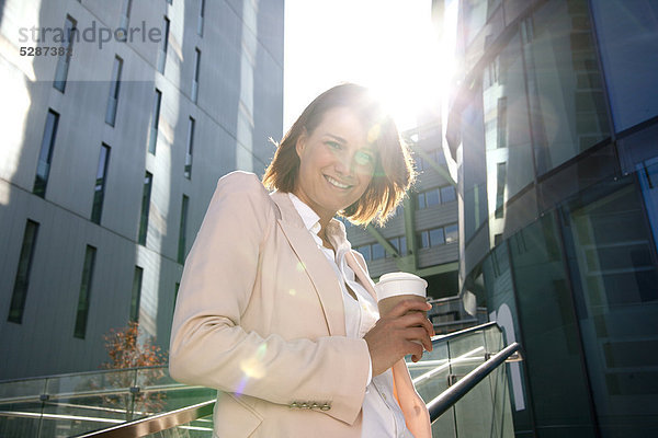 Lächelnde Geschäftsfrau mit Coffee to Go im Freien