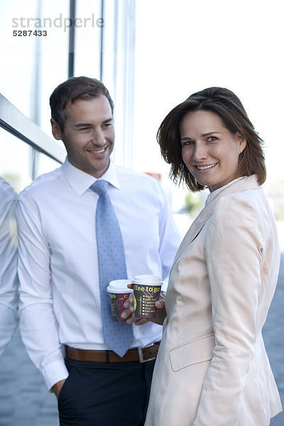 Geschäftsmann und Geschäftsfrau mit Coffee to Go unterhalten sich