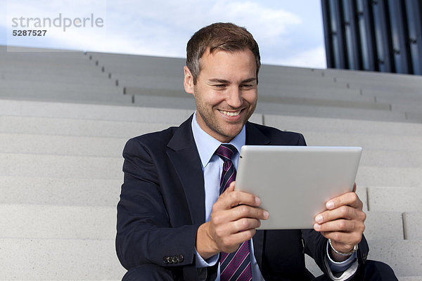 Geschäftsmann benutzt einen Tablet PC auf einer Treppe