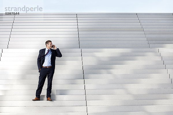 Telefonierender Geschäftsmann auf einer Treppe
