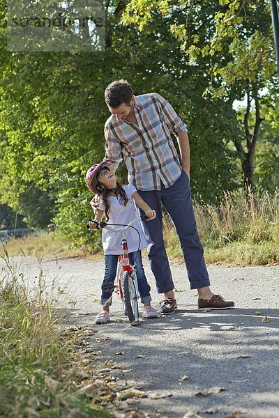 Vater und Tochter auf Fahrrad im Freien