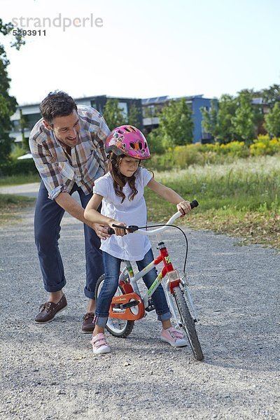 Vater hält Tochter auf Fahrrad im Freien