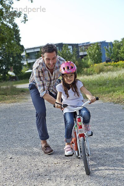 Vater hält Tochter auf Fahrrad im Freien