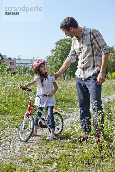 Vater und Tochter auf Fahrrad im Freien