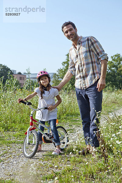 Vater und Tochter auf Fahrrad im Freien