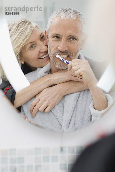 Mann beim Zähneputzen mit Frau