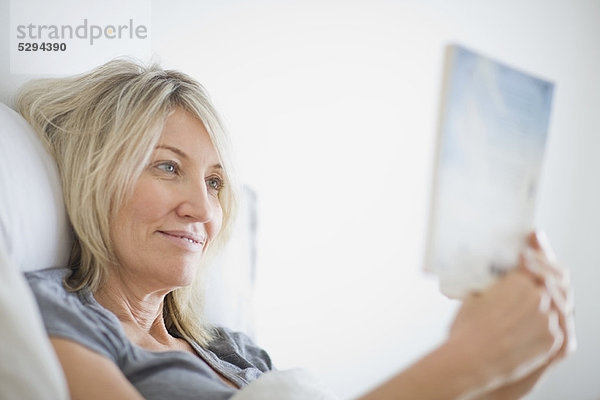 Frau liest Buch im Bett