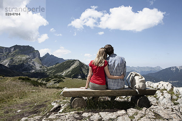 Paar sitzt auf einer Bank auf einem Hügel